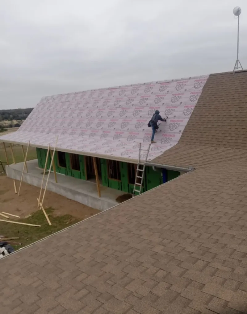 Worker preparing underlayment for a metal roof installation in Rib Mountain